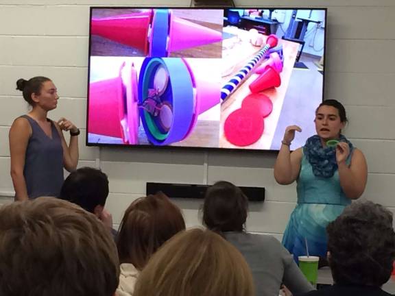 Seniors Josie Stolzenberg (l) and Julianna Schlichting (r) describe their invention of hiking poles that can charge phones and other digital devices.