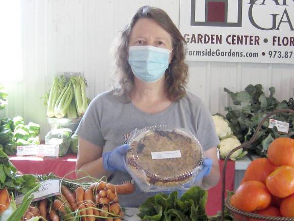 Market organizer Donna Traylor displays one of the delicious pies at the market. (She’s actually smiling behind her mask, BTW.) (Photo by Janet Redyke)