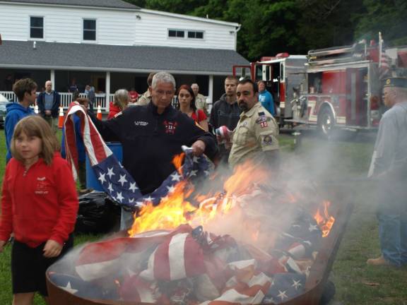 Photos by John Church Scouts line up to drop a flag into the fire.