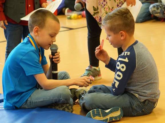 On left, Logan asks his volunteer to pick a card.