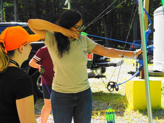 PHOTOS BY VERA OLINSKI From left, Jillian Banks instructs as soon to be instructor Danielle Lynise practices archery.
