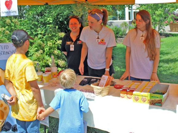 Shoprite at the fair Patty Gates (Flanders), Brandie Ellis (Long Valley), and Melissa Boffa (Sparta) give out goodies and prizes to young customers who donate to the ShopRite Partners in Caring campaign.