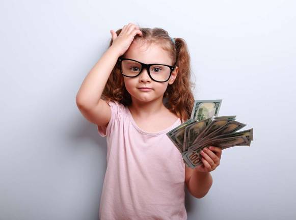 Teaching personal finance Small professor in eye glasses scratching head holding money and thinking how earring more. Kid have an big idea. Emotional portrait on blue background with empty copy space