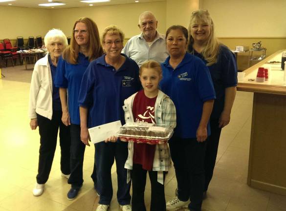 Amanda Witters presents a monetary donation and brownies to the Walkill Valley VFW. Amanda chose to honor and thank Veterans as a Random Act of Kindness for her Girls on the Run Vernon Team. In addition to community donations, Amanda's grandfather's VFW in Clifton was inspired by Amanda and also made a donation. The photo shows Amanda Witters with the Commander of the VFW post and the Veterans Women's auxiliary.