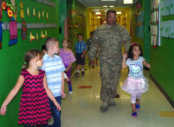 Army Sergeant First Class Roland Tajalle and his daughter Rai&#xfe;&#xc4;&#xf4;Ana, 5, walk down the main hall of Walnut Ridge Primary School.