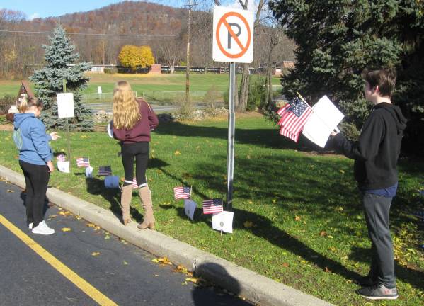 PHOTOS BY JANET REDYKE Eighth grade religious education students at St. Francis de Sales Church display flags on church grounds in honor of Veterans' Day.