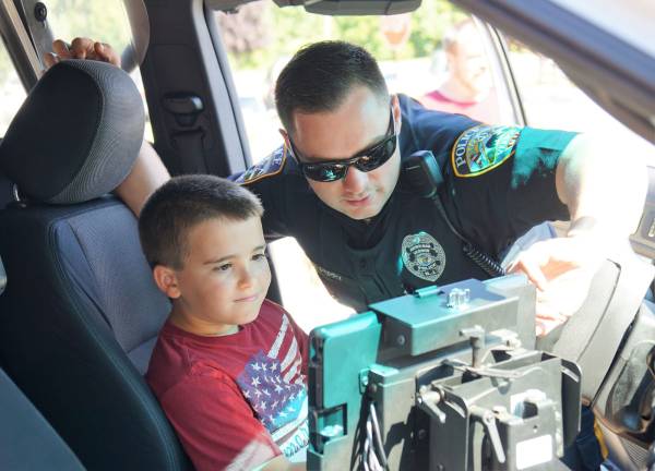 On right, Vernon Police Officer Perry explains how the siren, light, and GPS systems work.