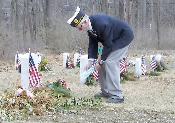 A veteran spreads ashes on a fellow veteran’s grave.