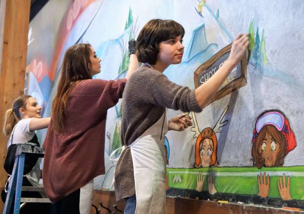 From left, students Sarah Biccum, Nikki Swiderski, and Cailey Pokrzywa create a new chalk mural in Schuss Bar.