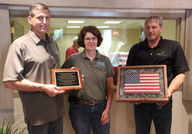 Reenee Casapulla, Sussex County Municipal Utilities Authority with Derek and Kevein Cooke, owners of Abbey Glen, holding grommit remains incased with a flag from last years Retired American Flag Ceremony.
