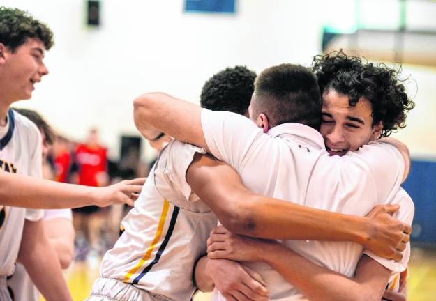 Assistant coach Kodie Hilbert hugs Alex Fessel and other players after the win.