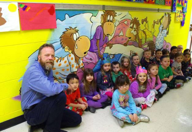 Wantage-based illustrator and artist Art Frisbie sits with Tina Leshnower&#xfe;&#xc4;&#xf4;s Kindergarten students under a monkey illustration meant to teach the children that they shouldn&#xfe;&#xc4;&#xf4;t jump on their beds.