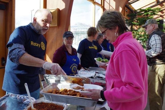 Sussex County Fairgrounds Manager and Rotary member Gary Larson serves Newton attorney Megan Ward some chicken wings at the buffet tables.