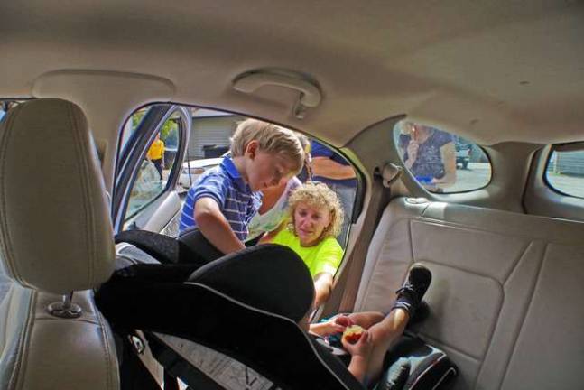 Newton Police Sergeant Dean Coppolella and Northern New Jersey Safe Kids Senior Checker Jackie Stackhouse make adjustments to a child car safety seat.