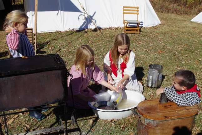 Young girls wash the breakfast dishes the &#x201c;old fashioned way.&#x201d;