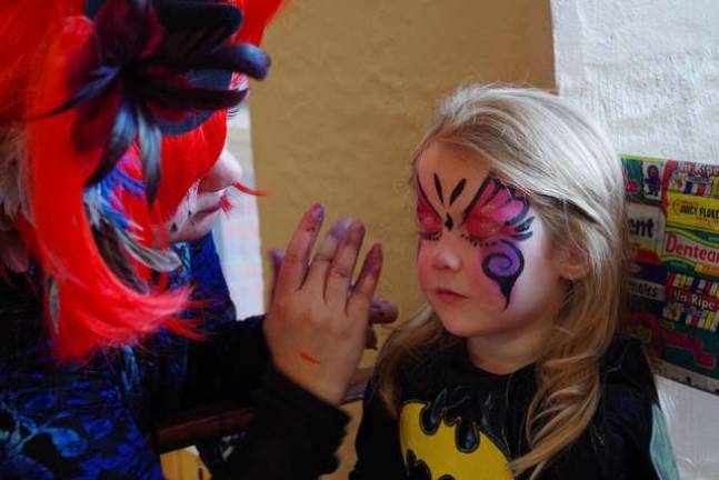 Barry Lakes Bat Girl Riley DeGrezia, 4, is shown getting her face painted by Kerry Tobin of Highland Lakes, better know as Pixie Pop the Clown.