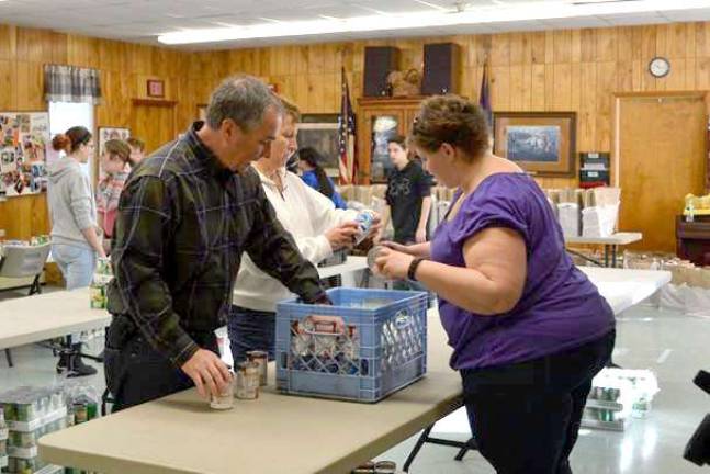 Labor Commissioner Harold J. Wirths (plaid shirt) and his wife, Debbie (white shirt), help volunteers package Thanksgiving meals for nearly 100 needy families as part of an annual food drive coordinated by the Sussex Help Center.