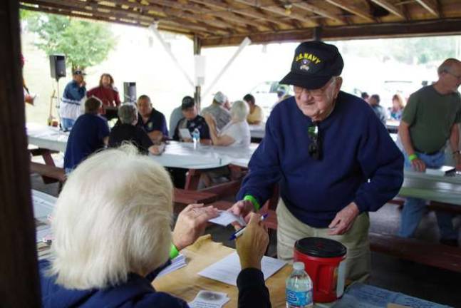 PHOTOS BY CHRIS WYMAN Korean War Navy veteran Vincent Grey of Vernon hands a completed information form to Sussex Elks volunteer Carol Lee Spages. For Grey, it was his first year at the veterans picnic.
