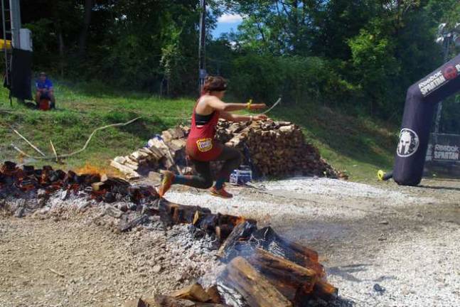 Heading towards the finish line, Spartan racers jump across flaming logs as the last obstacle in the race to receive their completion medals.