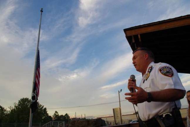 With flags at half-mast in the background, Vernon Township Police Department Chief Randy Mills accepts an award for his department for its service to the people of Vernon.