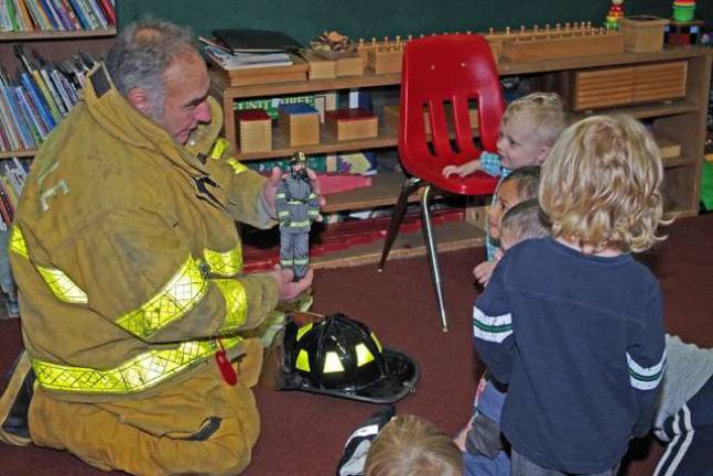 Bob Winter uses a small firefighter doll to explain the heavy fire-resistant clothing and even an oxygen tank mounted to the figurine&#x2019;s back.