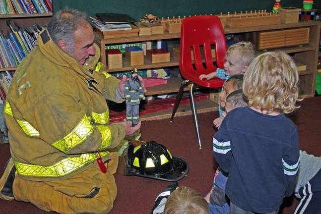 Never too young to learn about fire safety Bob Winter uses a small firefighter doll to explain the heavy fire-resistant clothing and even an oxygen tank mounted to the figurine’s back.