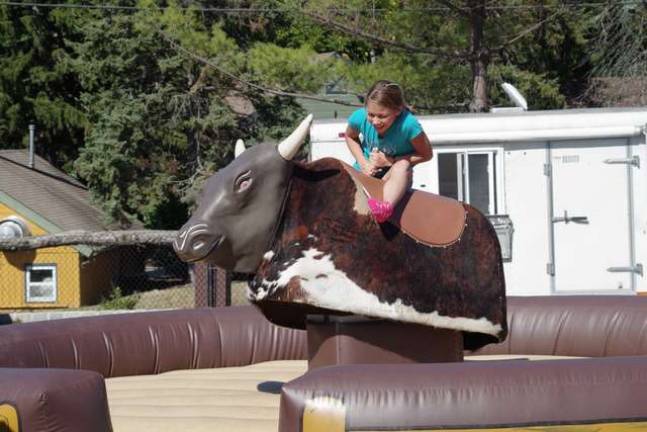 A young girl tries out the mechanical bull that was available.
