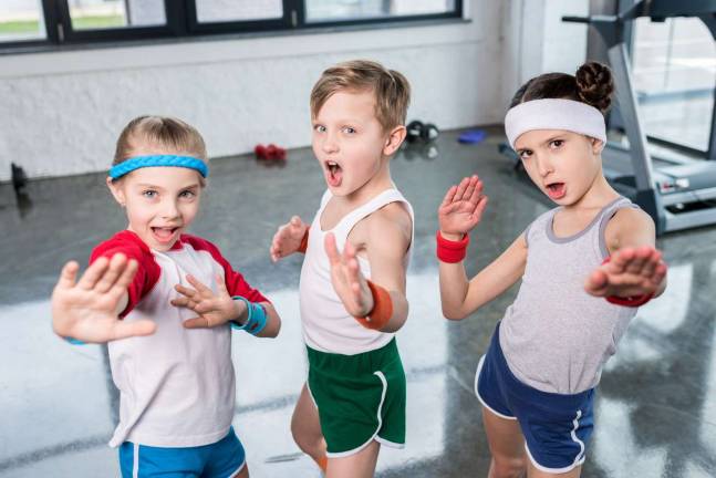 Group of little kids in sportswear exercising and posing at camera in gym children sport school concept