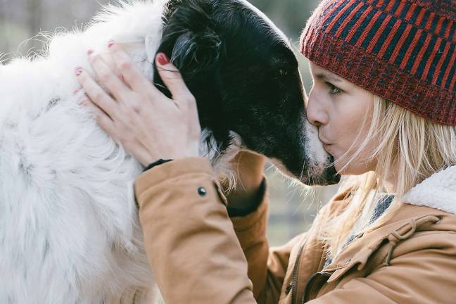 At some colleges, no need to be separated from a beloved pet Beautiful woman kissing her dog outdoors. Girl with her dog. Cute dog loves her owner.