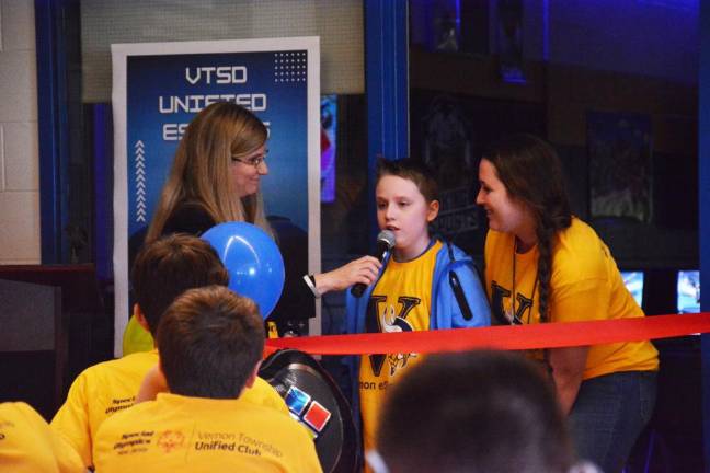 Glen Meadow Middle School Principal Jacquelyn Van Orden hands the mike over to sixth-grade student Christian Katz, as Glen Meadow Middle School Paraprofessional Taylor Dely stands beside him.