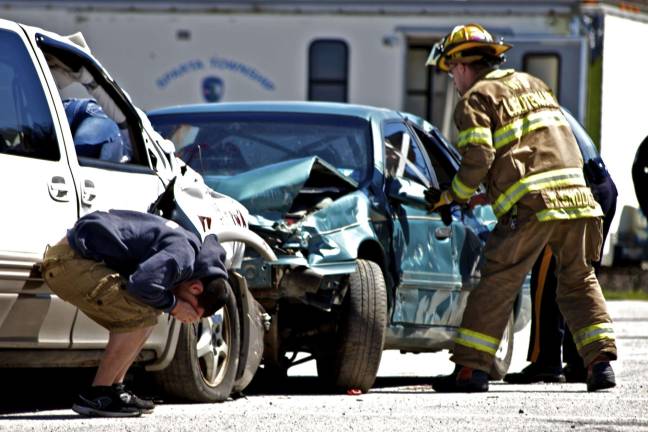 Staged fatal crash A firefighter attempts to enter the damaged car as the driver is doubled over with grief.