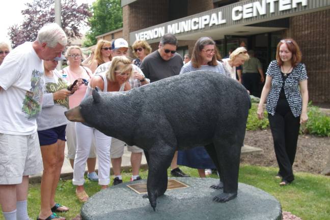 Black bear statue unveiled at town hall Visitors inspect the statue.