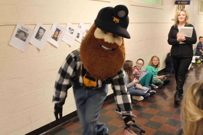 Adrienne Sprung and Herbie, Mascot both of Sussex County Miners walking through Wantage School's halls as classes sit for D.E.A.R. time (Drop Everything And Read) on Read Across America Day. Fourth-grade students shown to right of Mascot Herbie, from left to right, are Sophia Lemanski, Arielle Anderson, and Madison Mahouchick. To the right of Adrienne Sprung is fourth grader Dylan Masters.