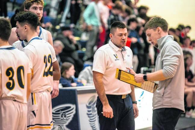 Assistant Coach Kodie Hilbert, left, and Coach Connor Healy go over a play during a time out.