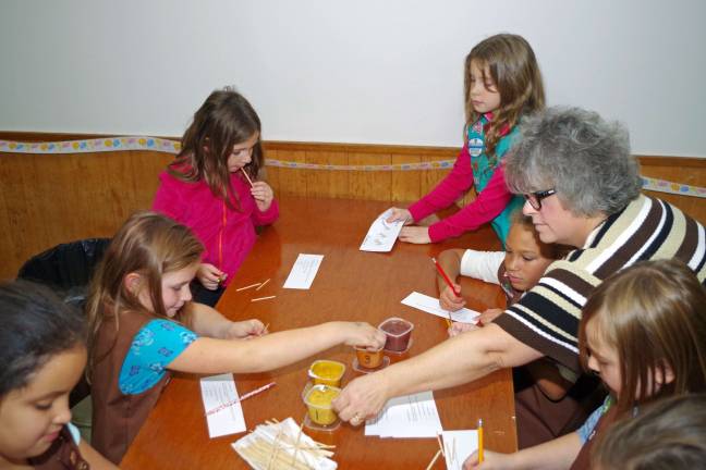 The girl scouts are shown trying several samples at the &quot;mystery baby food tasting.&quot;