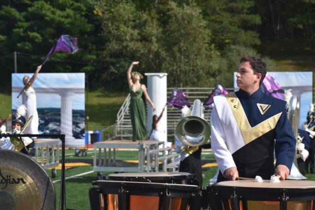 Members of the color guard strike poses behind the musicians.