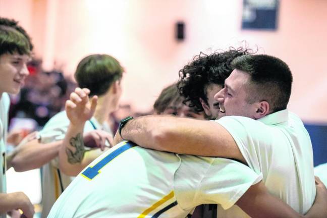 Assistant coach Kodie Hilbert hugs Alex Fessel and other players after the win.