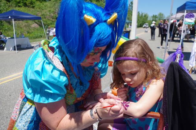 Emma Bray, 4, of Vernon carefully watches the construction of her purple flower tattoo as it is created by Kerry Tobin of Highland Lakes, better know as Pixie Pop the Clown.