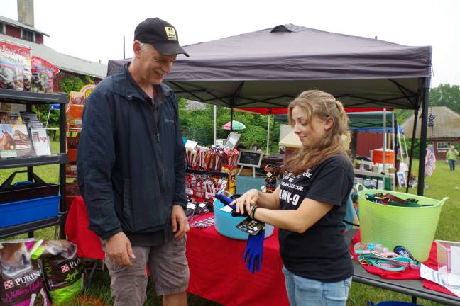 John Kuperus, owner of Farmside Supplies in Sussex Borough, brought a selection of horse feed and horse-related accessories. He is shown here with Sharon Leigh, an animal portrait artist, who came to the festival from Palmyra in Burlington County. He was trying on a pair of waterproof gloves.