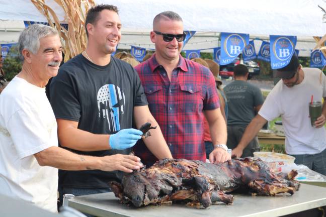 Vernon Police Officer Kenneth Kuzicki (Center) poses with what has become a yearly tradition in Glenwood Estates and Colonial Oaks, the roast pig of Oktoberfest.