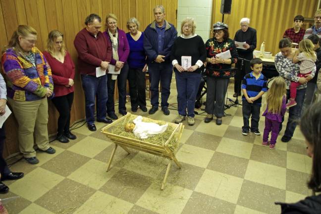 Church members and visitors stand around the manger, which was blessed with holy water by Father Bob.