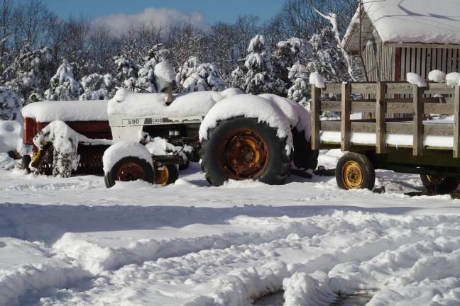 A tractor and hay wagon remain snow covered at High Breeze Farm on Barrett Road in Vernon.