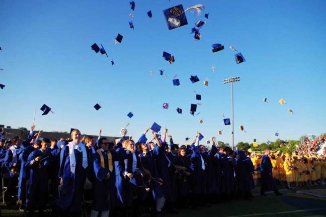 Students in the graduating class toss their caps to the sky.