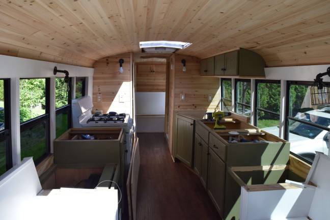 Photo by Erika Norton The inside of the &quot;skoolie&quot; features three couch/beds, a stove, a sink, cabinets, a full shower and a composting toilet.
