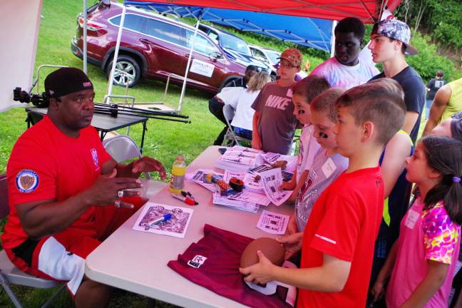 Children gather to punt, pass and kick Former NY Giants running back Lee Rouson signs autographs and speaks to young fans.
