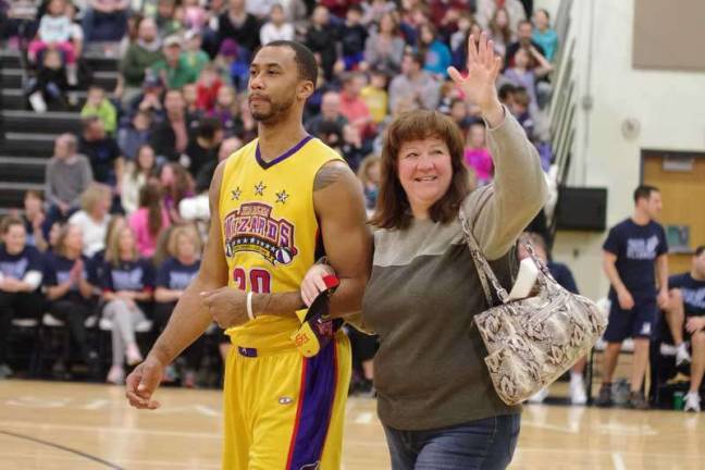 Harlem Wizard Timothy &quot;Tomahawk&quot; Stukes escorts Sparta resident Tracey Puleo back to her seat after helping retrieve her pocketbook swiped by one of his teammates.