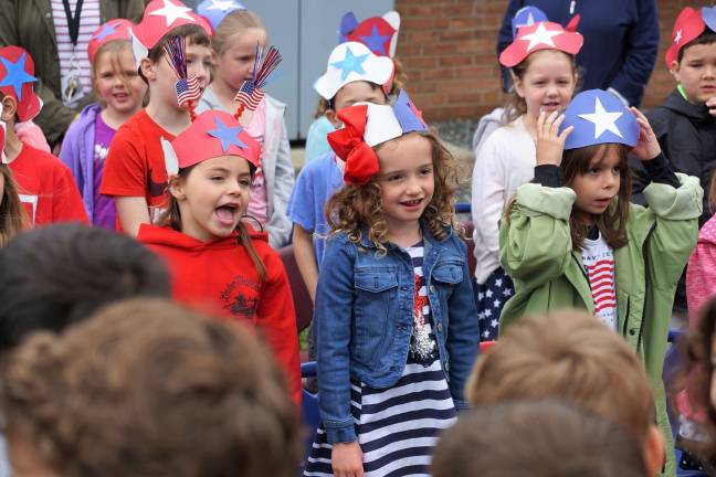 Kindergartners sing patriotic songs with gusto.