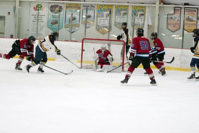 Vernon's Rick Bennett, second from left, hits the puck toward the goal in the second period of the game against Newton/Lenape Valley on Feb. 3. He scored one goal, and Vernon won, 11-6. (Photos by George Leroy Hunter)