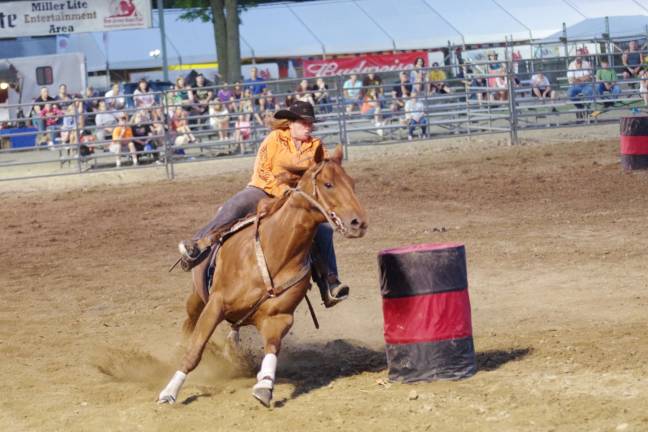 A rodeo cowgirl and her horse advance in the barrel racing contest.