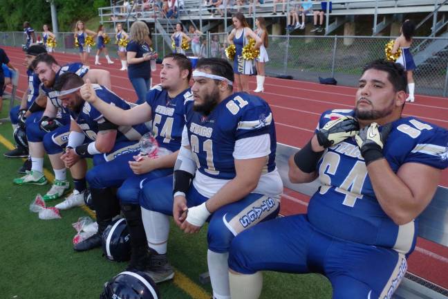 Several members of the Sussex Stags offensive line take a break on the bench.